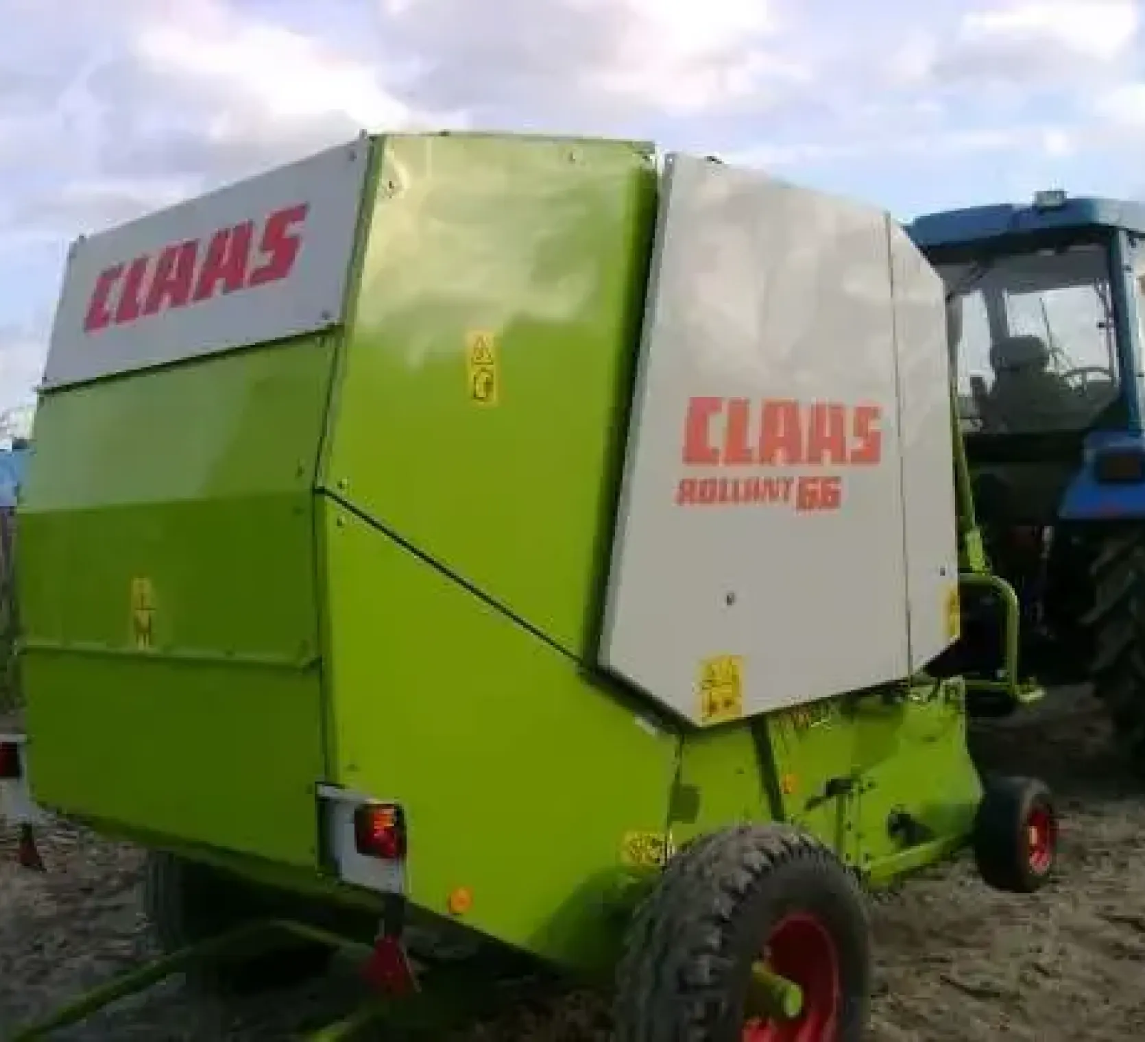 Używana Prasa zwijająca walcowa Claas Rollant 66 podczas jazdy z ciągnikiem 