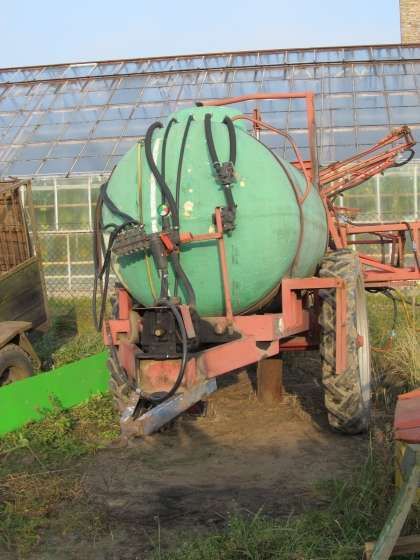 Opryskiwacz używany Rauch 2000 l belka 18 m  na tle szklarni 