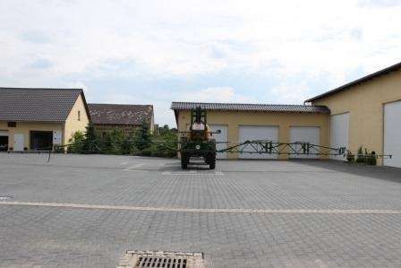 Używany Opryskiwacz Amazone UG3000 Nova na utwardzonym placu w tle budynki gospodarcze