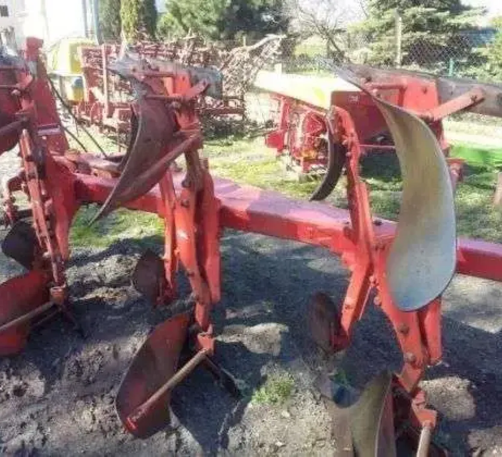 Używany pług obracany 4 skibowy, Kuhn Multimaster zaprezentowany na tle innych używanych maszyn rolniczych z gospodarstwa sprzedającego 