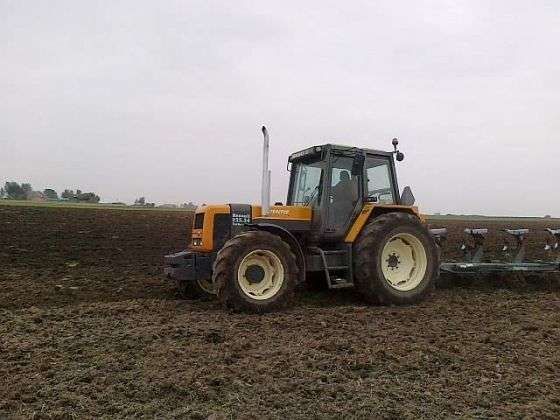 Używany ciągnik rolniczy Renault 155.54 z zamontowanym pługiem podczas orki 