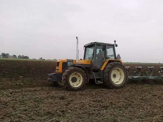 Używany ciągnik rolniczy Renault 155.54 z zamontowanym pługiem podczas orki 