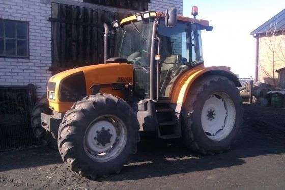 Używany żółty traktor rolniczy Renault Ares 550 RX w zabudowaniach gospodarstwa 