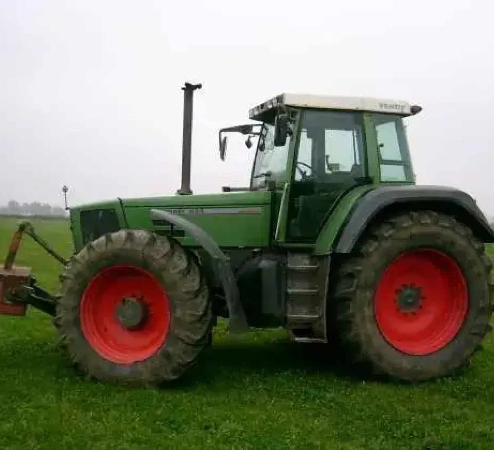 Zadbany ciągnik rolniczy marki Fendt seria 824 z 1996 roku zaprezentowany na polu z uniesionym obciążnikiem przednim 