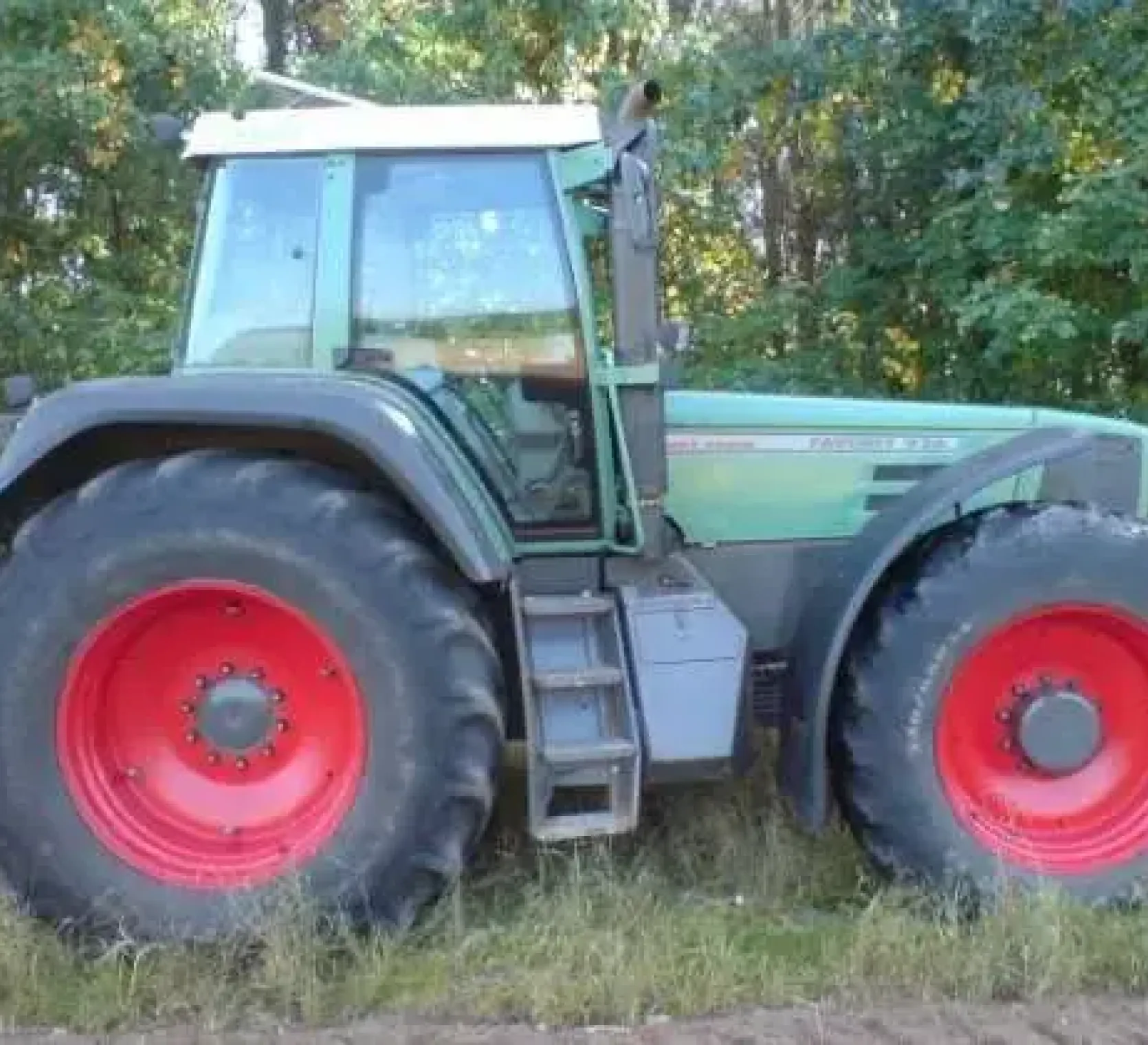 Używany ciągnik rolniczy Fendt 926 Vario widok na prawy bok na tle zarośli 