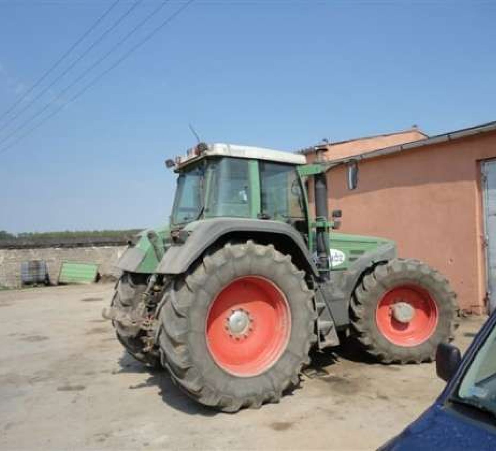 Praawy bok używanego ciągnika Fendt Favorit 824 na tle zabudowań gospodarczych 