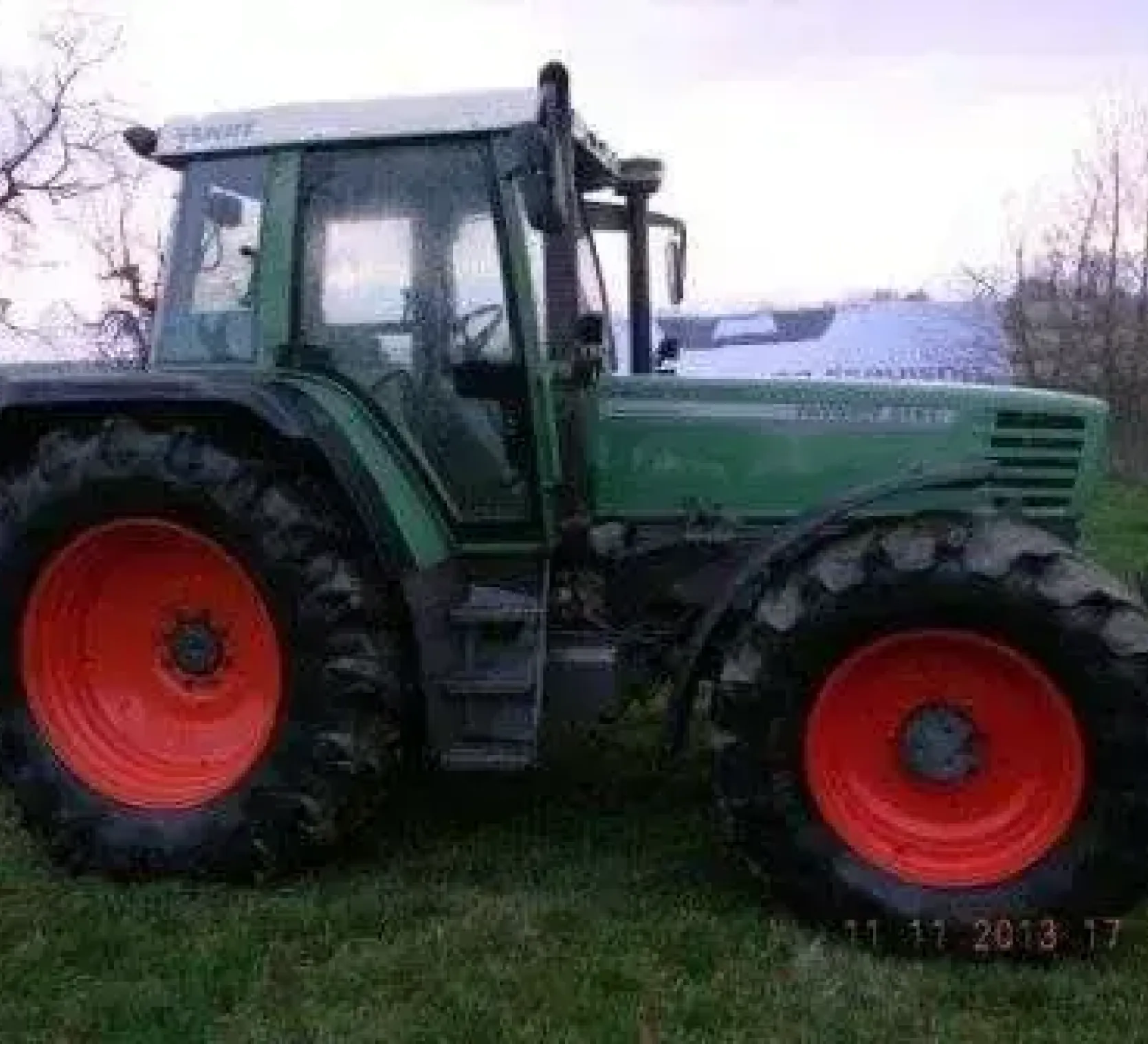 Używany ciągnik rolniczy Fendt 515 C widok na prawy bok pojazdu stojącego na łące 