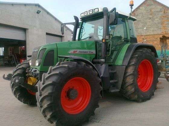 Zielony ciągnik niemieckiego producenta Fendt 714 Vario w zabudowaniach gospodarstwa 