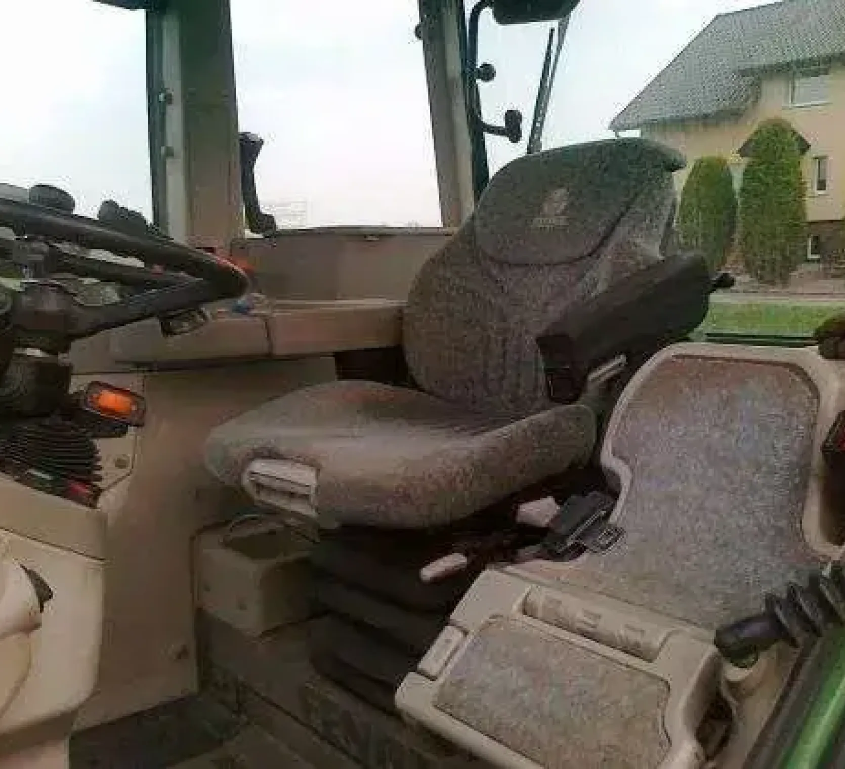 Widok na siedzenie kierowcy oraz pasażera oraz kierownicę we wnętrzy używanego ciągnika rolniczego Fendt 716 Vario 