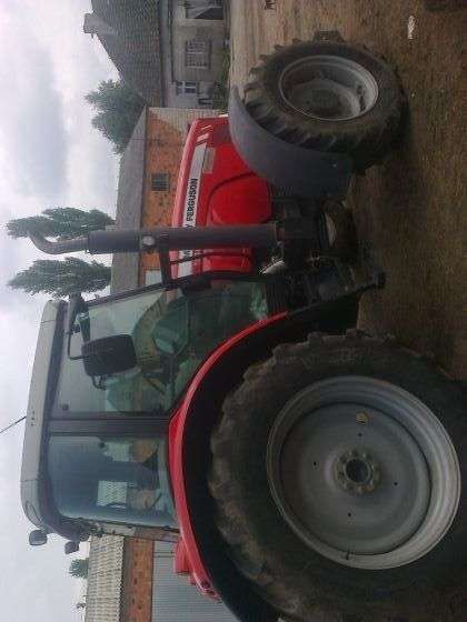 Ujęcie z boku na ciągnik rolniczy marki Massey Ferguson 5465 na tle gospodarstwa, kabina, koła, korbanek.pl