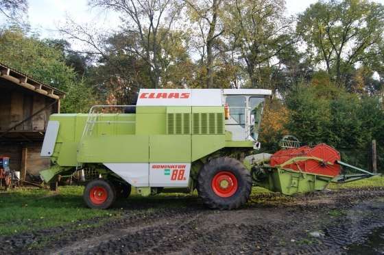 Używany Kombajn zbożowy Claas Dominator 88s widok z prawej strony na tle wysokich drzew