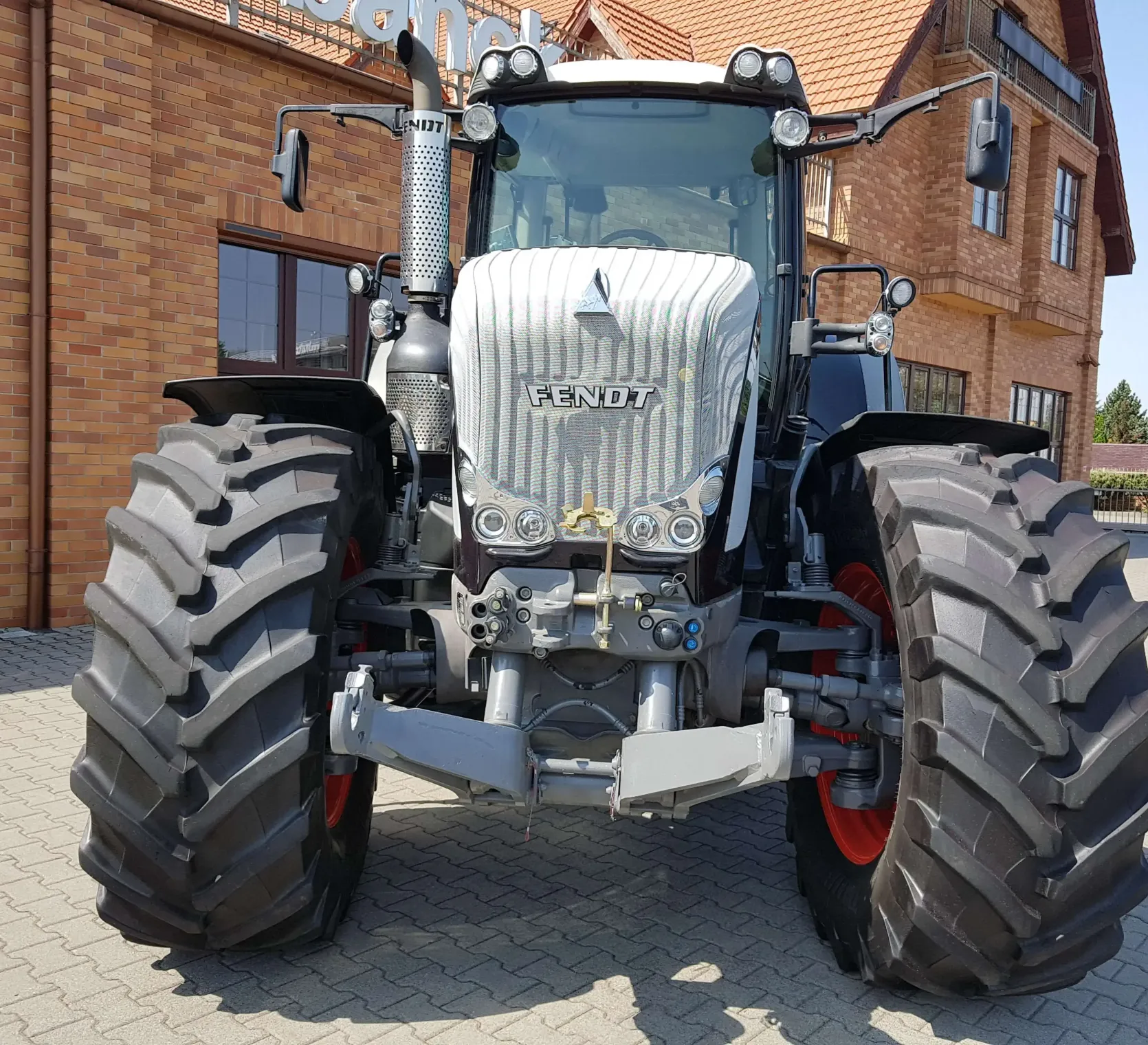 Używany czarny ciagnik Fendt 936 widok z przodu na tle klinkierowego budynku