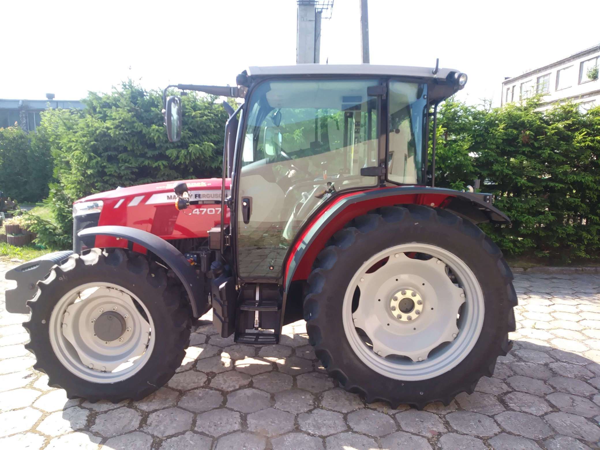 OKAZJA! Na sprzedaż Ciągnik MF 4707 zdjęcie na tle zielonego żywopłotu