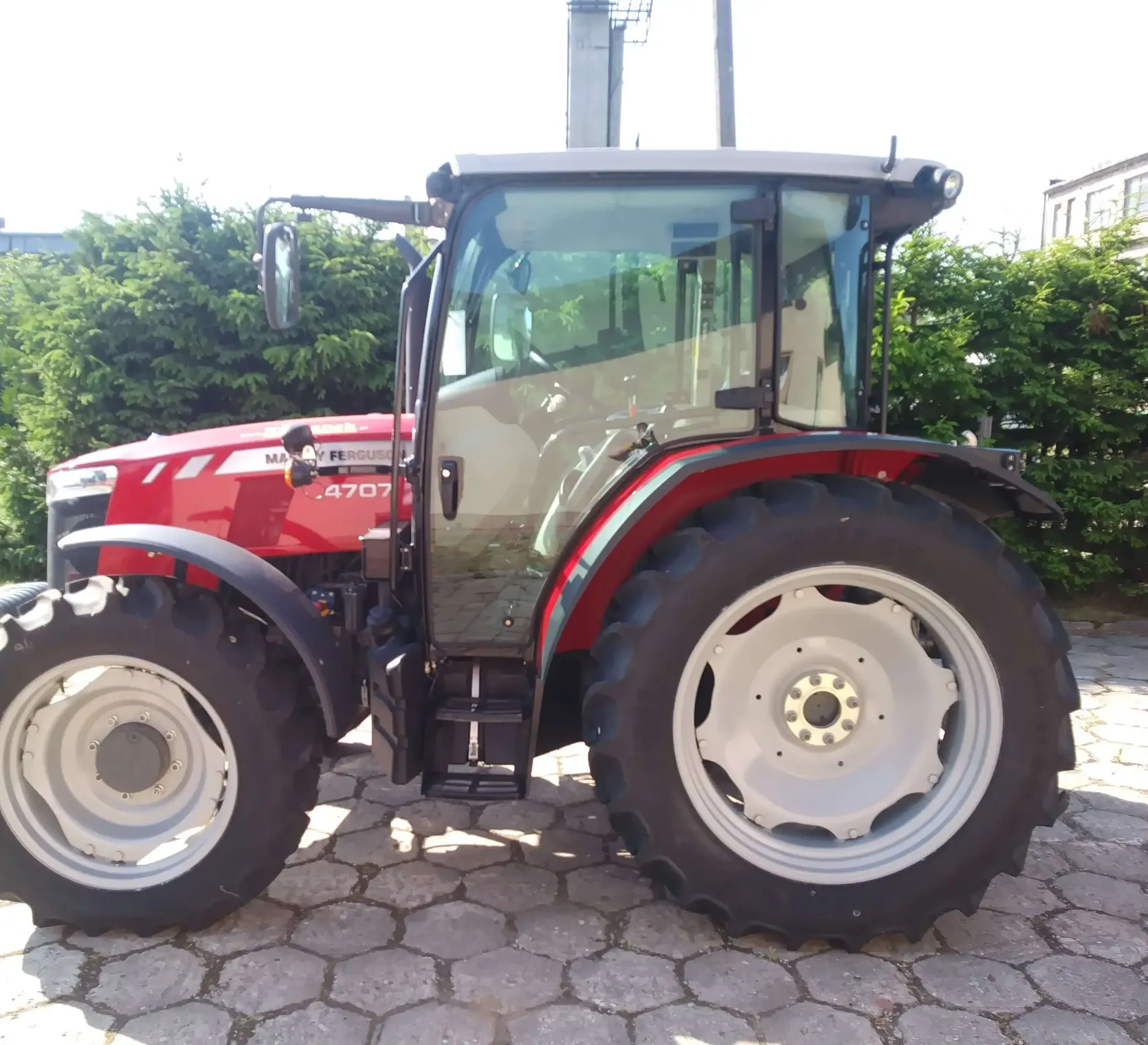 OKAZJA! Na sprzedaż Ciągnik MF 4707 zdjęcie na tle zielonego żywopłotu