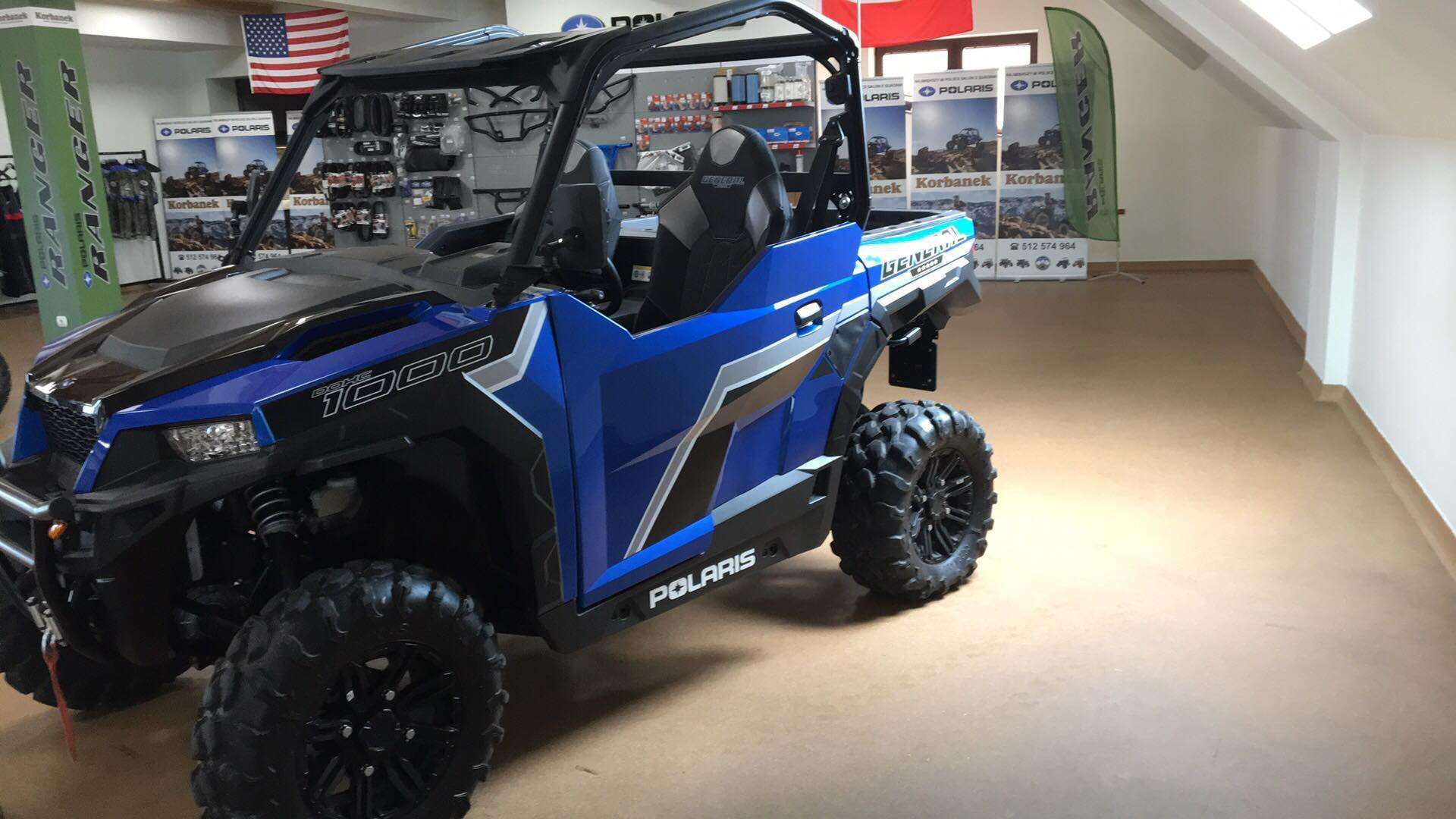 Ciągnik rolniczy Polaris General 1000 XP Premium EPS na tle akcesoriów do quadów w salonie Polari spółki Korbanek