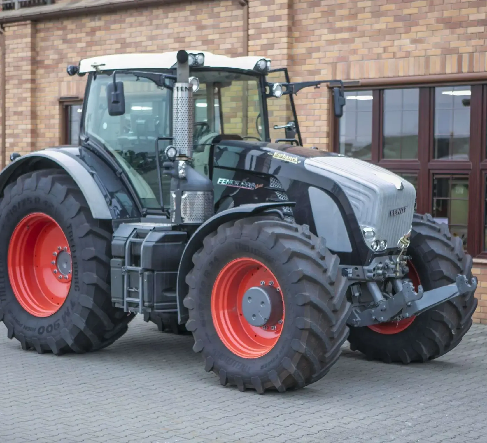 Czarny traktor Fendt 936 z 2013 roku zdjęcie z lewej strony na tle klinkierowej ściany z dużymi oknami