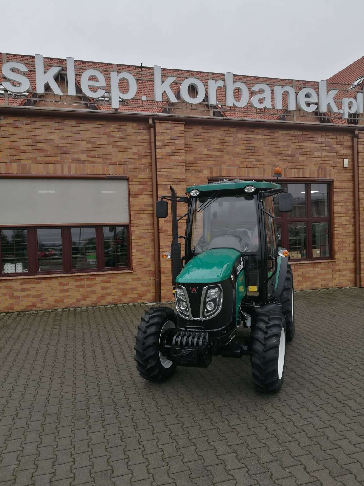 Ciągnik Arbos 3055 na tle firmy Korbanek