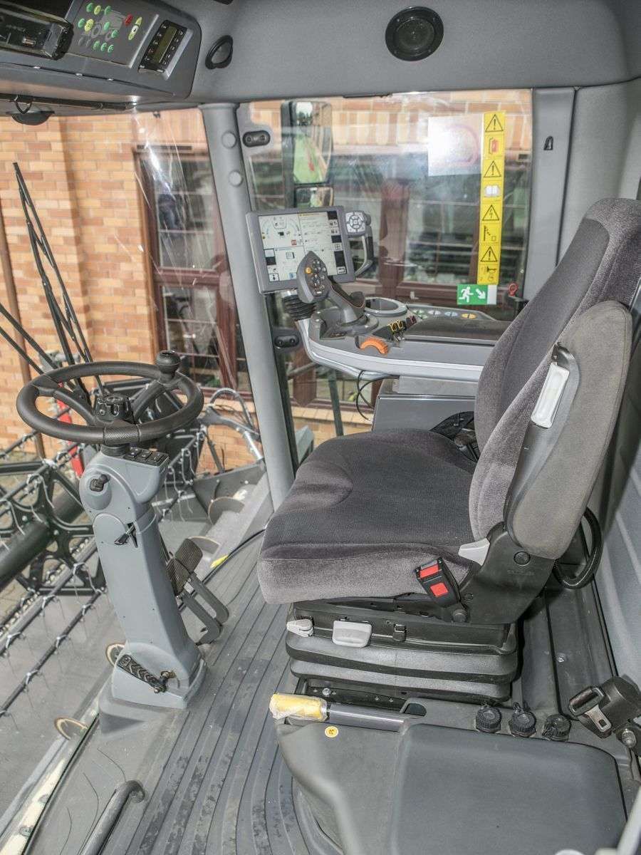 Wnętrze kabiny używanego kombajnu Fendt 6335 widok na kierownice i siedzenie operatora  