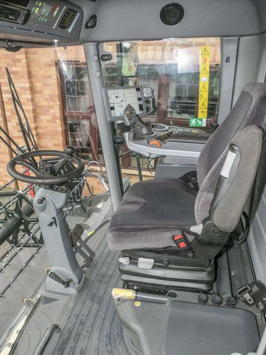 Wnętrze kabiny używanego kombajnu Fendt 6335 widok na kierownice i siedzenie operatora  