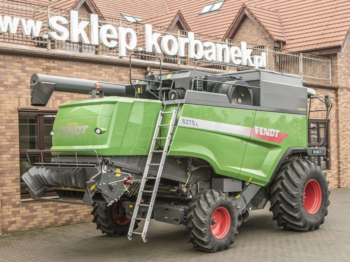 Prawy bok używanego kombajnu Fendt 6275 L  na tle sklepu części zamiennych społki Korbanek 