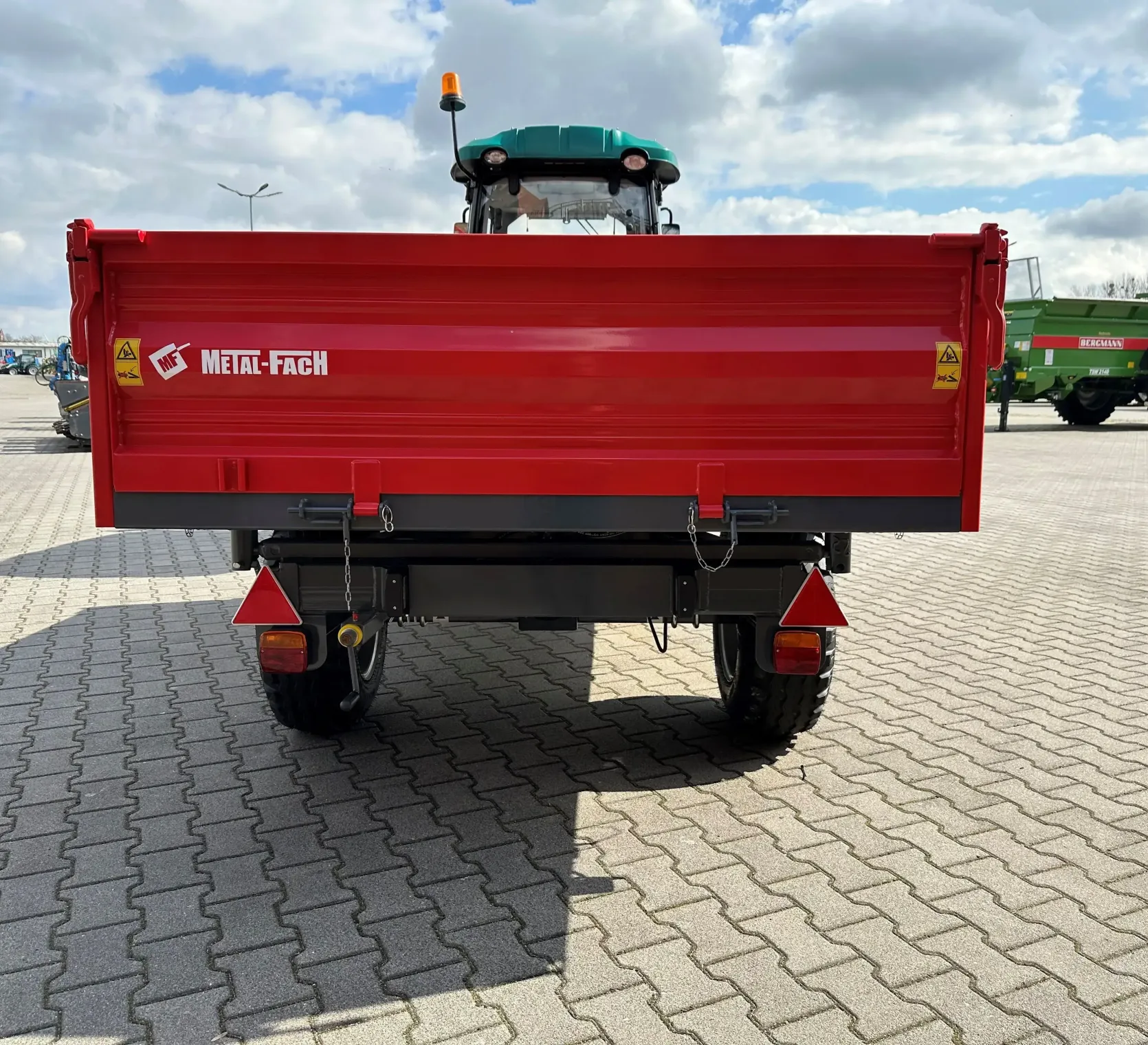 Czerwona przyczepa wywrotka T735C/1 o ładowności 3200 kg firmy Metal-Fach podczepiona do ciągnika ARBOS 3055