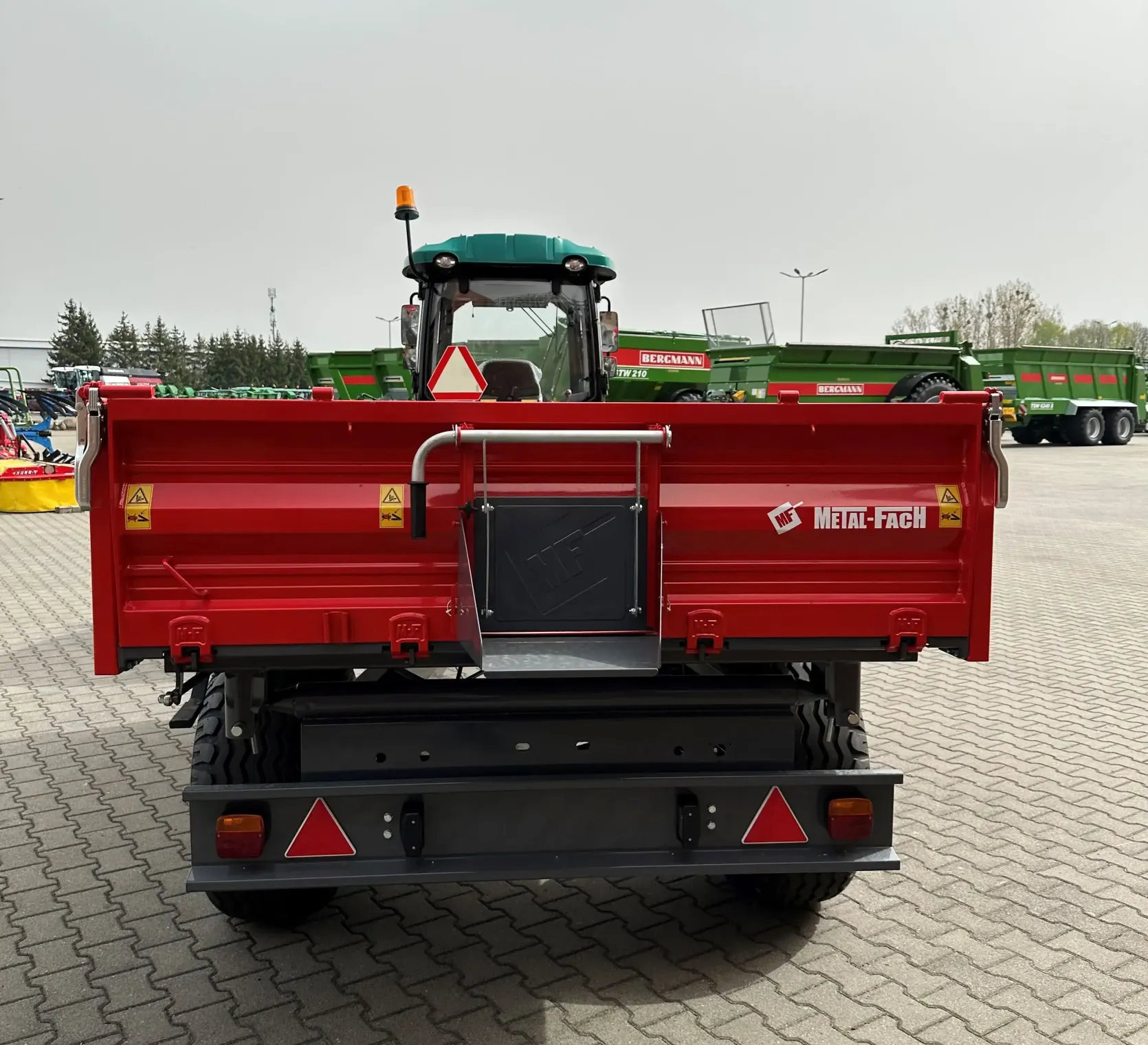 Czerwona przyczepa wywrotka T703A/1 o ładowności 3800 kg firmy Metal-Fach podczepiona do ciągnika ARBOS 3065