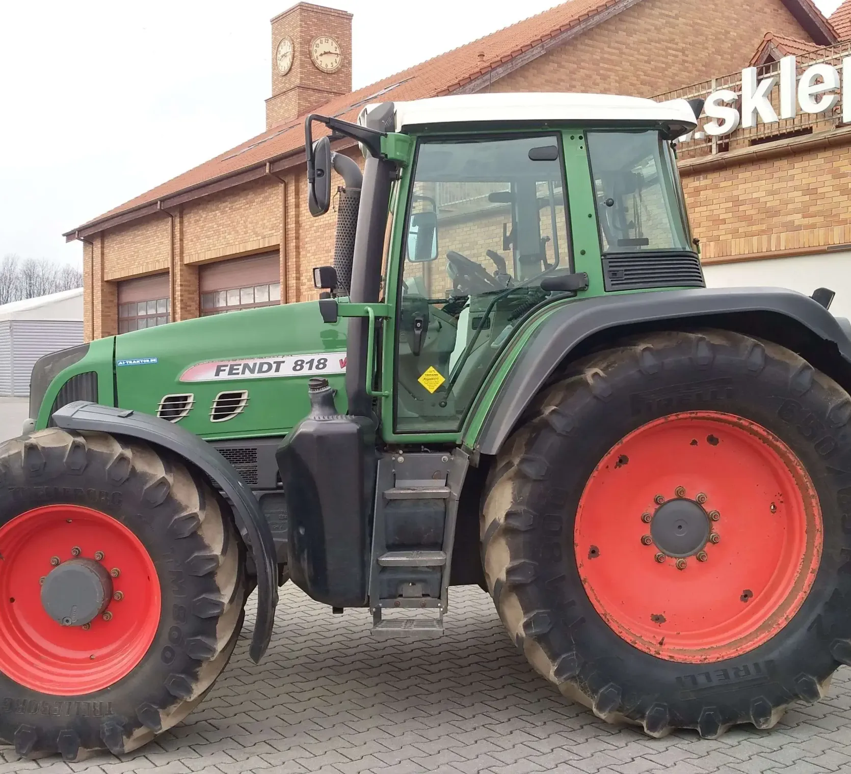 Ciągnik Fendt 818 Vario TMS na tle magazynu części Korbanek widok lewego boku