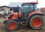 Lewy bok ciągnika m7060 marki kubota na tle gospodarstwa rolnego