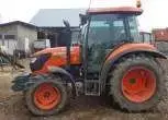 Lewy bok ciągnika m7060 marki kubota na tle gospodarstwa rolnego