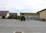 Używany Opryskiwacz Amazone UG3000 Nova na utwardzonym placu w tle budynki gospodarcze