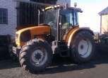 Używany żółty traktor rolniczy Renault Ares 550 RX w zabudowaniach gospodarstwa 