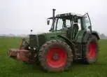 Używany ciągnik rolnicz Fendt 924 rocznik 1996 zaprezantowany na zielonym tle pola z czerwonym obciążnikiem przednim 