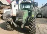 Używany ciągnik rolniczy Fendt 312 Vario widok na przód pojazdu na tle zabudowań gospodarczych 