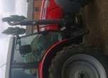 Ujęcie z boku na ciągnik rolniczy marki Massey Ferguson 5465 na tle gospodarstwa, kabina, koła, korbanek.pl