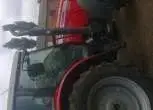 Ujęcie z boku na ciągnik rolniczy marki Massey Ferguson 5465 na tle gospodarstwa, kabina, koła, korbanek.pl