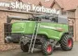 Prawy bok używanego kombajnu Fendt 6275 L  na tle sklepu części zamiennych społki Korbanek 