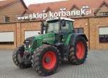 Ciągnik Fendt 818 Vario TMS na tle magazynu części Korbanek widok z lewej strony
