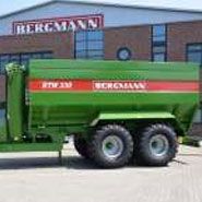 Przed budynkiem produkcyjnym firmy Bergmann stoi przyczepa do przeładunku zboża typ GTW koloru zielonego z napisem GTW Bergmann