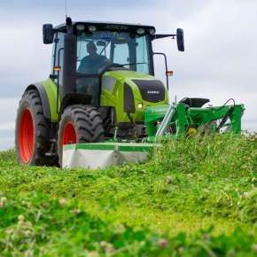 Zielony traktor rolniczy podczas koszenia łąki na siana za pomocą kosiarki czołowej bębnowej KBF firmy samasz www.korbanek.pl