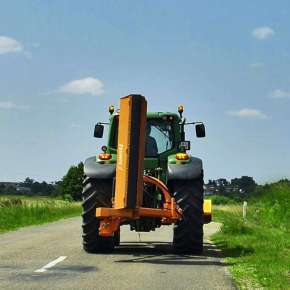 Widok z tyłu kosiarki bijakowej tylno-bocznej KBRP 200 złożonej do pozycji transportowej na zielonym traktorze rolniczym www.korbanek.pl