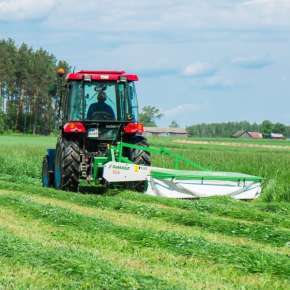 Czerwony traktor rolniczy z kosiarka rotacyjną bębnową firmy Samasz kosi trawę na pastwisku www.korbanek.pl