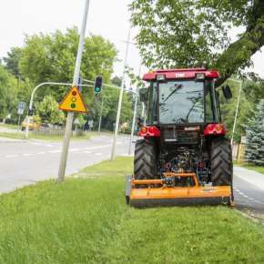 Pomarańczowa kosiarka mulczująca PIKO 130 wraz z traktorem rolniczym mulczuje trawę na poboczu drogi i w parku www.korbanek.pl