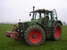 Używany ciągnik rolnicz Fendt 924 rocznik 1996 zaprezantowany na zielonym tle pola z czerwonym obciążnikiem przednim 