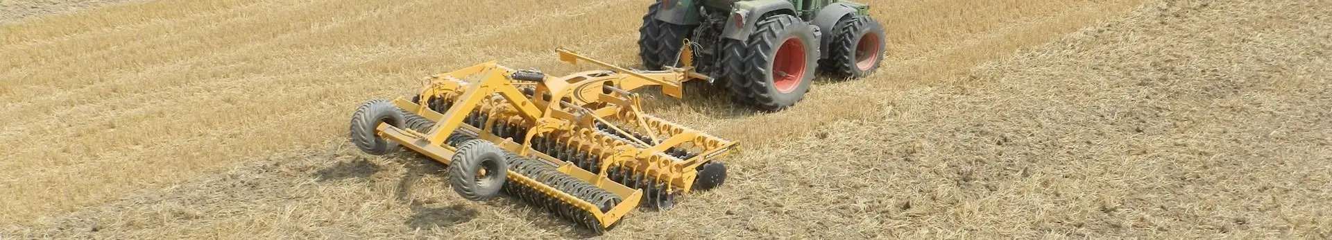 Agregat podorywkowy firmy Agrisem typ Disc-O-Mulch Żółty agregat Agrisem Disc-O-Mulch pracuje na polu z ciągnikiem korbanek.pl